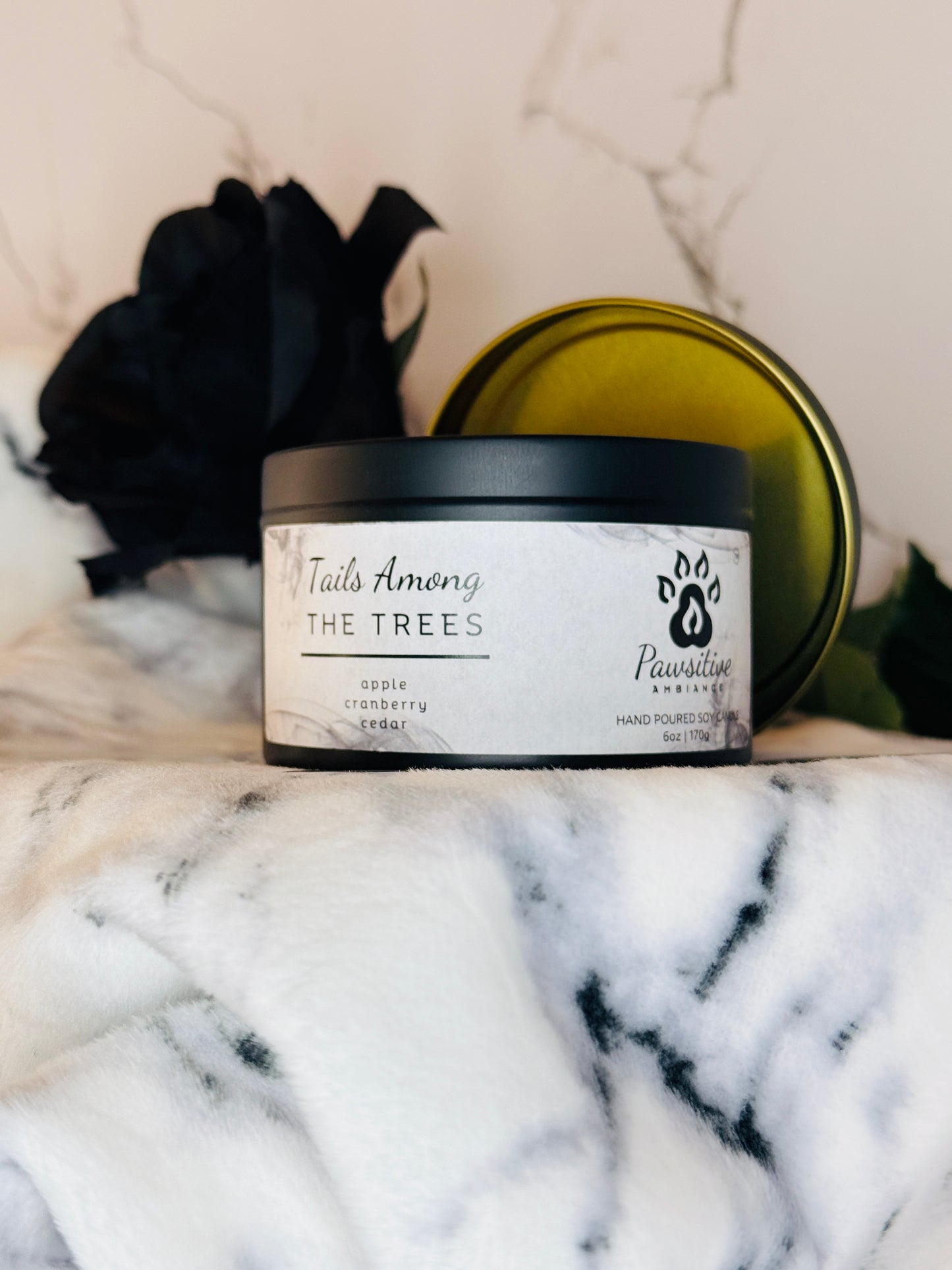 Hand-poured soy candle labeled Tails Among the Trees featuring notes of apple, cranberry and cedar. 6 oz. Manufactured by Pawsitive Ambiance.