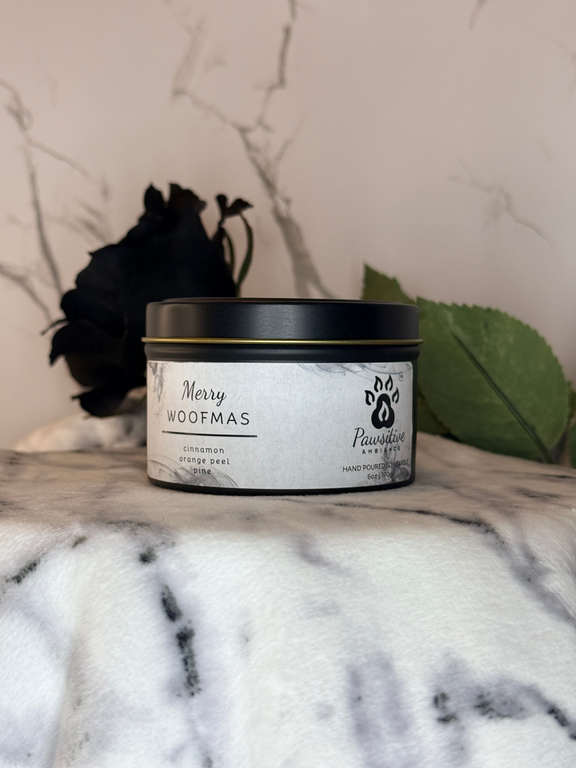 Hand-poured soy candle labeled Merry Woofmas featuring notes of cinnamon, orange peel and pine.  6 oz. Manufactured by Pawsitive Ambiance.