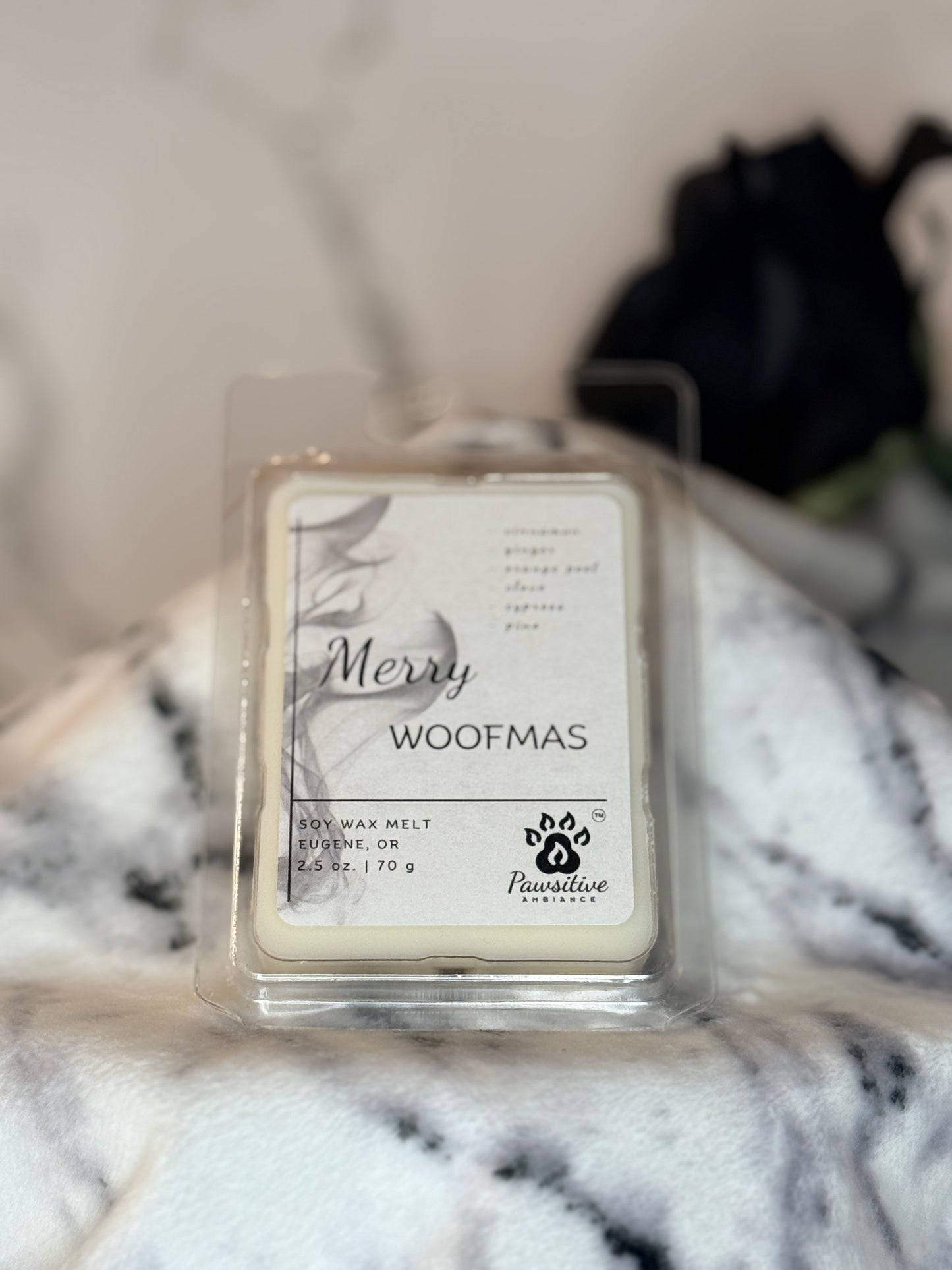 Hand-poured wax melt labeled Merry Woofmas featuring notes of cinnamon, ginger, orange peel, clove, cypress and pine.  2.5 oz. Manufactured by Pawsitive Ambiance.
