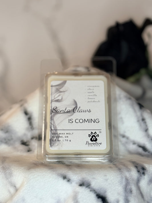 Hand-poured wax melt labeled Santa Claws is Coming featuring notes of cinnamon, clove, apple, vanilla, lemon and patchouli.  2.5 oz. Manufactured by Pawsitive Ambiance.
