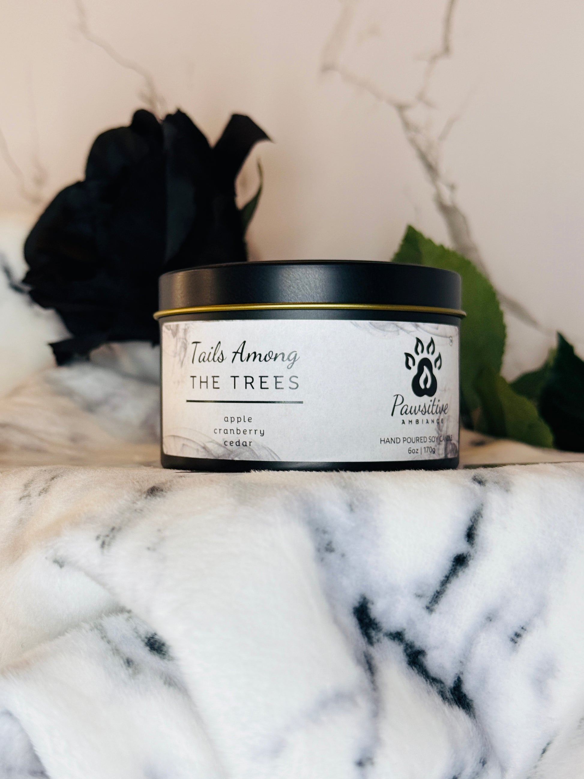 Hand-poured soy candle labeled Tails Among the Trees featuring notes of apple, cranberry and cedar.  6 oz. Manufactured by Pawsitive Ambiance.